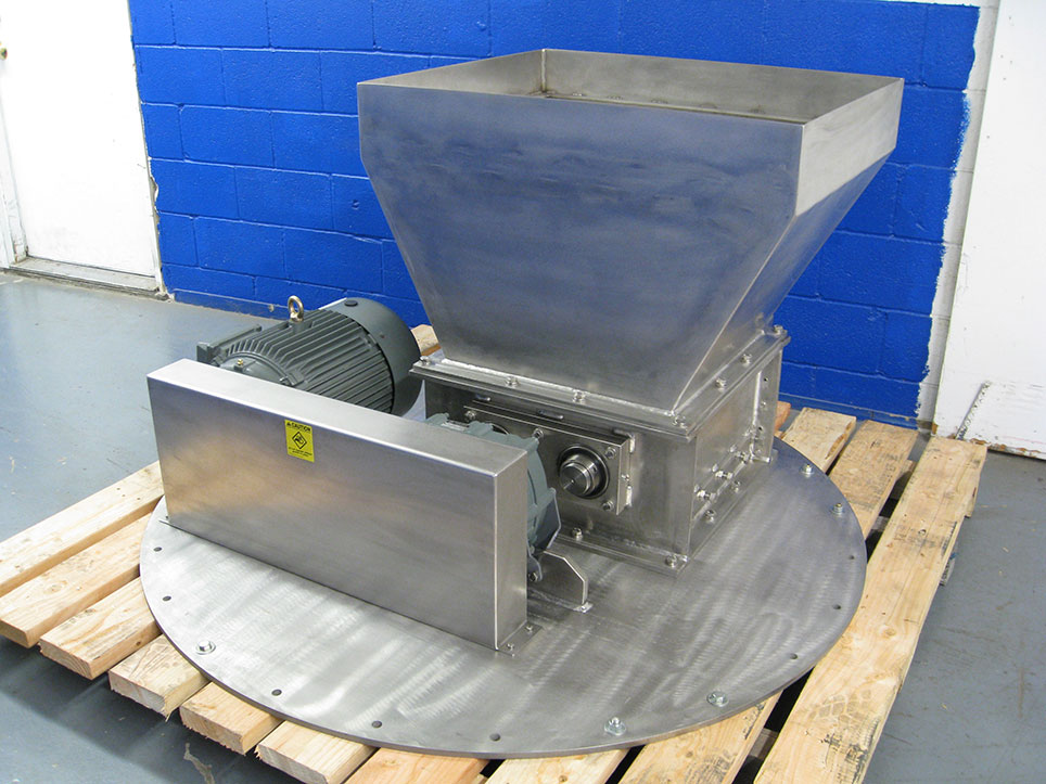 A Model 2020 stainless steel lump breaker on a round plate on a wooden platform.